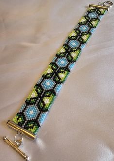 a bracelet made out of beads and some scissors on a white sheet with a silver clasp