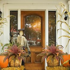 two scarecrows are sitting on hay in front of a door with pumpkins