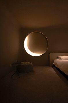 a bedroom with a bed and a round light fixture in the middle of the room