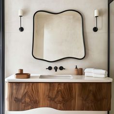 a bathroom vanity with a mirror above it and two lights on the wall behind it