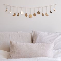 a white bed topped with lots of pillows next to a wall mounted crescent moon phases