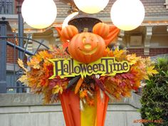 a sign that says halloween time is decorated with pumpkins and leaves in front of a building