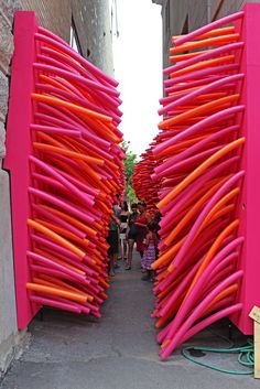 there are many pink and orange objects in this alley way that look like they have been made out of sticks