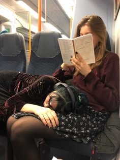 a woman reading a book while laying down on a train with her head in her hands