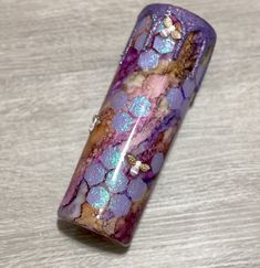 a close up of a glass object on a wooden table with white and purple colors