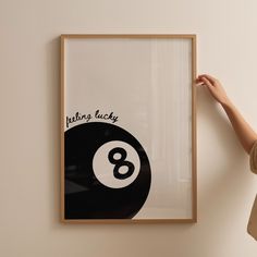 a woman is holding up a poster with the number eight ball on it in front of a white wall