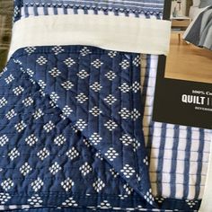 a bed with blue and white quilts on top of it next to a pillow