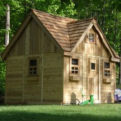 a small wooden house sitting in the middle of a lush green field next to trees