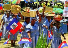 several women in blue dresses holding flags and baskets on their heads at an outdoor event