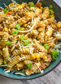 a bowl filled with pasta and vegetables on top of a wooden table