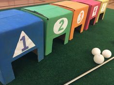 four different colored boxes with numbers and golf balls on the ground next to each other