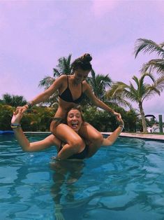 two women are in the pool playing with each other while one woman is on her back