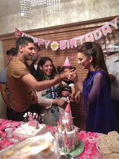 a group of people standing in front of a birthday cake