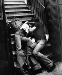 black and white photograph of two people sleeping on stairs