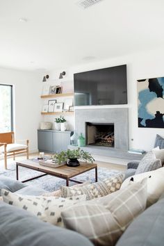 a living room filled with furniture and a flat screen tv mounted on the wall above a fire place