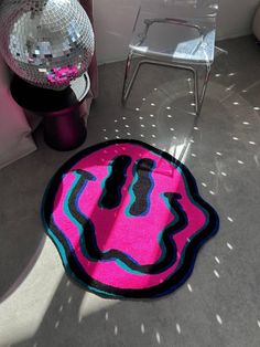 a pink rug sitting on top of a floor next to a chair and disco ball