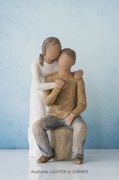 a ceramic figurine of a man holding a woman sitting on top of a stool