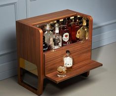 a wooden cabinet with liquor bottles and glasses in it on the floor next to a wall