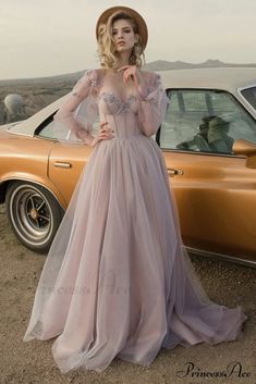 a woman standing next to a car wearing a dress with sheer shoulders and long sleeves