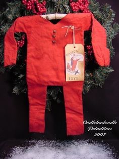 a red baby's outfit hanging from a christmas tree with snow on the ground