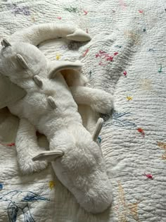 a white stuffed animal laying on top of a bed