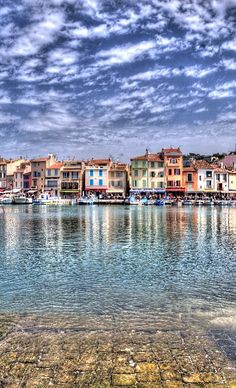 there are many boats that are in the water near some buildings on the other side of the river