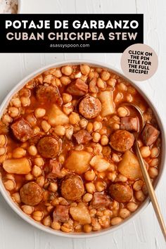 a white bowl filled with beans and sausage next to a spoon on top of a table