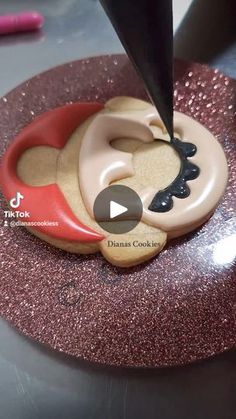 a cookie being decorated with fondant and icing on top of a pink plate