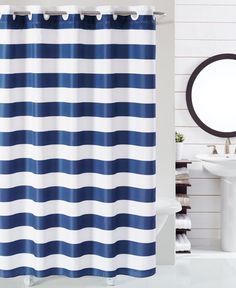 a blue and white striped shower curtain next to a sink with a mirror on the wall