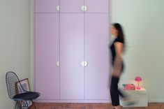 a woman is walking in front of a purple cabinet