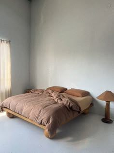 a bed sitting in the middle of a room next to a lamp and window with curtains