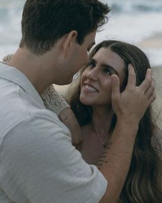 a man and woman standing next to each other near the ocean