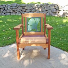 a wooden chair sitting on top of a sidewalk next to a grass covered park area