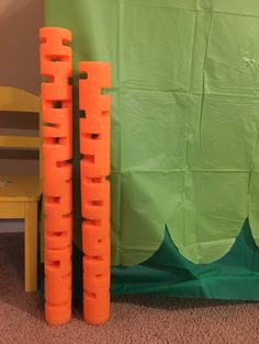 there are two plastic orange blocks on the floor next to a chair and green wall