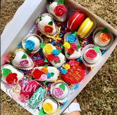 a box filled with lots of colorful cupcakes on top of a carpeted floor