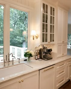 a kitchen with lots of white cabinets and counter top space next to a large window