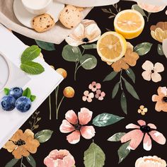 a table topped with cookies and fruit next to a plate filled with oranges, blueberries