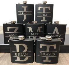 six black and silver flasks with the letters f, t, m, d