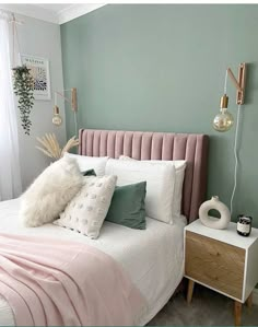 a bedroom with mint green walls and white bedding, pillows and blankets on the headboard