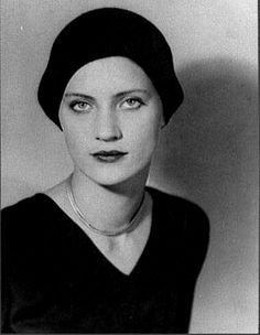 an old photo of a woman wearing a black dress and a beanie on her head