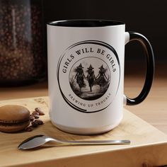 a white and black coffee mug sitting on top of a cutting board next to a spoon