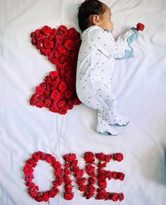 a baby laying on top of a bed covered in red flowers next to the word love