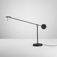 a black and white photo of a desk lamp on a gray surface with the light turned off