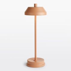 an orange lamp on a white surface with a light brown base and a beige shade