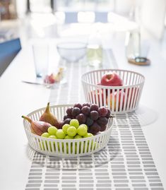 two white baskets filled with fruit sitting on top of a table