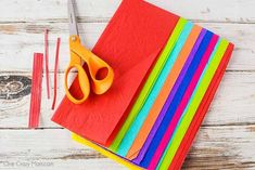 a pair of scissors sitting on top of colored papers