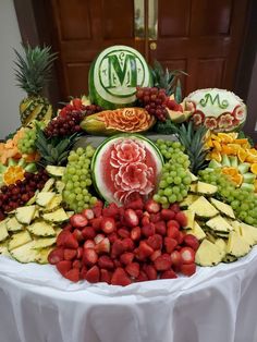 a fruit platter with grapes, melons, pineapples and watermelon