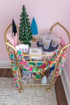 a gold bar cart filled with cups and candy canes next to a christmas tree