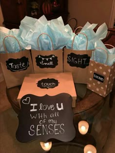 small bags with writing on them are sitting on a table next to candles and some tea lights