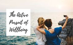 two people standing on the edge of a cliff looking out at the ocean and holding their arms around each other